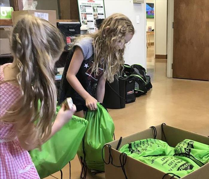 Two girls pack stuffed animals into bags