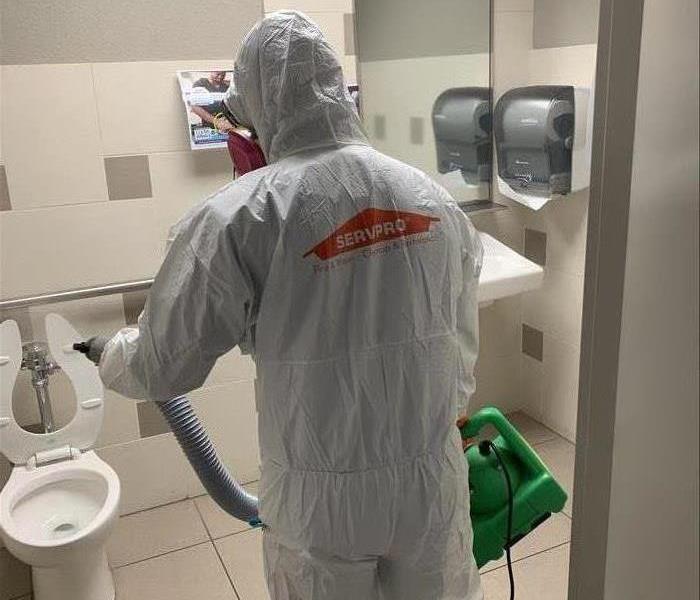man in white PPE in bathroom