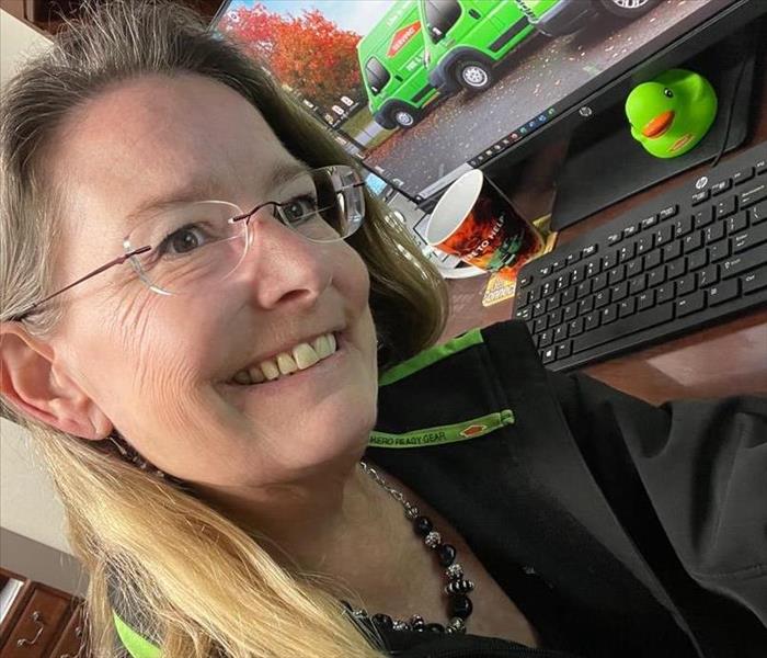 blonde lady at desk, SERVPRO trucks and duck in background